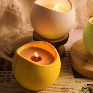 Dettaglio di candele profumate accese in barattoli di ceramica su vassoio in legno