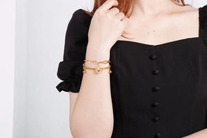 Detail of double-layer gold sunburst coin pendant bracelet on model wrist