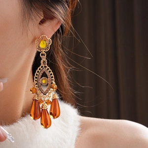 Close-up of vintage tassel earrings with tiger eye stone and crystals on a model