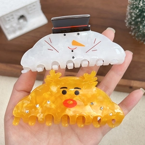 Cute Christmas hair claws with white snowman and amber reindeer designs on wood background