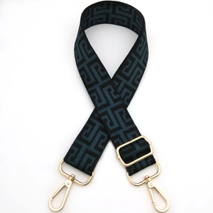 Detail of adjustable maze pattern bag strap with green weave and gold metal hooks