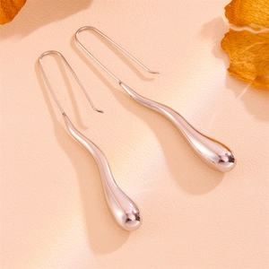 Macro view of teardrop earrings in polished titanium steel on a leather surface