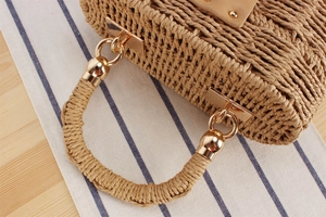 Detail shot of the khaki straw woven bag texture with gold metal rings and handle