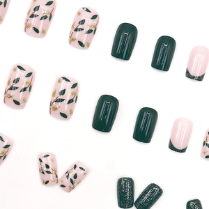 Green leaf and gold glitter press-on nails with French glitter tips on white background