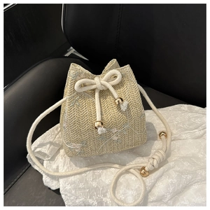 Detailed embroidery of pastel flowers on a woven bucket bag with drawstring closure