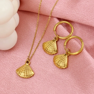 Ensemble collier et boucles d'oreilles coquillage doré sur un tissu en soie rose