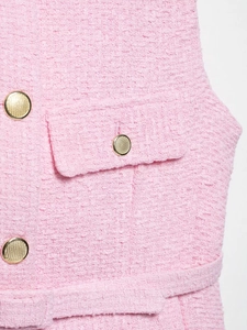 Détail de la texture en tweed rose avec bouton en métal doré et décoration de poche