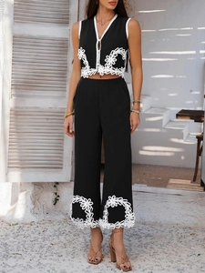 Détail de la broderie florale blanche sur le haut sans manches noir et le pantalon large