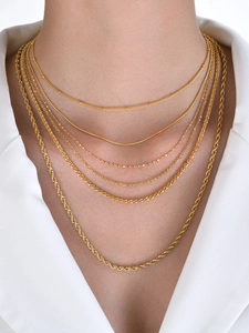 Detail view of tiered 18k gold plated titanium steel chain necklaces on a model