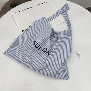 Close-up of blue and white striped canvas tote bag with Sunday typography on white table