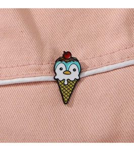 Close-up of a cute penguin ice cream enamel pin on pink denim fabric with white piping
