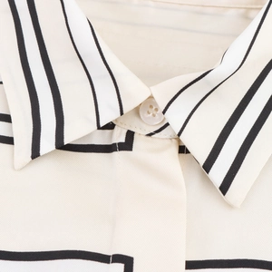 Close-up of minimalist cream satin shirt with black stripes and a button collar