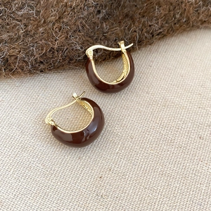 Detailed close-up of brown enamel gold-tone C-shaped earrings with metallic clasp