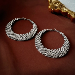 Macro shot of silver woven hoop earrings with clear rhinestones on dark fabric