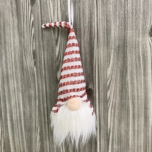Close-up of Nordic Christmas gnome with red striped hat and white beard on wood background