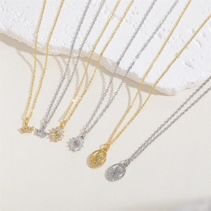 Close-up of gold and silver necklaces with zircon pendants on white stone background