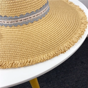 Detail of straw sun hat featuring blue lace ribbon and raw edge woven texture