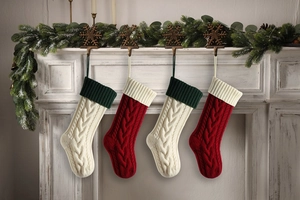 Detail of four cable knit Christmas stockings in red and beige on a fireplace mantle