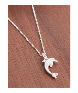 Detailed close-up of a silver S925 dolphin pendant necklace on a dark wooden surface