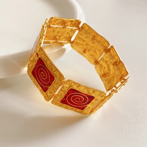 Detail of vintage square enamel bracelet with gold hammered metal and red spiral motifs