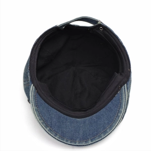 Internal view of a washed blue denim flat cap with black lining and adjustable strap