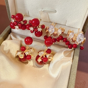 Dettaglio di orecchini con perle rosse e zirconi su un portagioie in raso color champagne