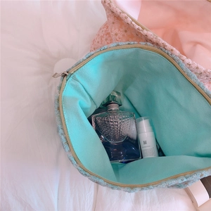 Detailed close-up of daisy embroidery and metal zipper on mint green lace bag