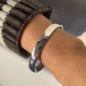 Dettaglio di un bracciale rigido in acciaio inossidabile lucido su una maglia intrecciata
