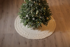 Detailed close-up of beige knitted Christmas tree skirt with diamond weave pattern