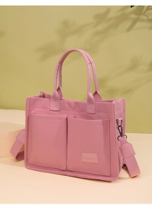 Detailed shot of pink canvas tote bag showing front pockets and detachable shoulder strap