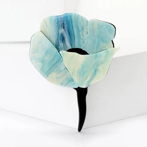 Detail of blue and white marble resin flower hair clip with glitter finish on white background