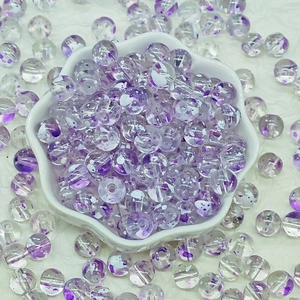 Macro detail of 8-10mm purple floral glass beads in a white flower shaped dish for DIY