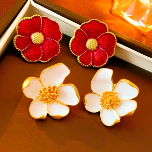 Detailed close-up of red and white enamel flower stud earrings with vintage golden edges