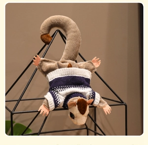 Detail of sugar glider plush wearing a striped sweater hanging on a black iron frame