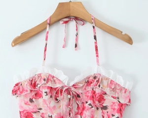 Detail of pink floral halter top with lace trim and button accents on a wooden hanger