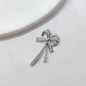 Silver bow pendant necklace with pearls and zircon tassels on a white background