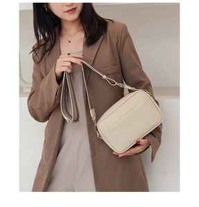 Detail of beige litchi grain PU leather crossbody bag with wide striped textile strap