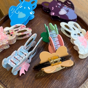 Macro shot of assorted acetate rabbit and butterfly hair claws on a wooden display tray