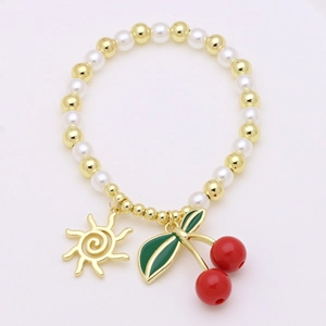 Beaded pearl bracelet with golden sun charm and red cherry pendant on white background
