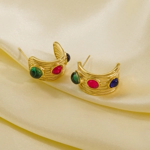 Detailed shot of C-shaped 14K gold earrings with red green and blue gemstones