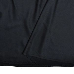 Vue détaillée de la texture du tissu noir brillant avec une couture soignée sur le bord