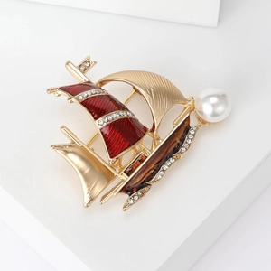 Detail of sailboat brooch with red enamel, sparkling rhinestones and a white pearl