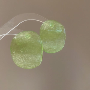 Macro detail of light green translucent resin earrings with a brushed texture finish