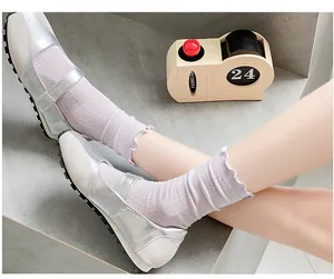 Close-up of lavender knit socks with ruffle edges paired with silver Mary Jane sneakers
