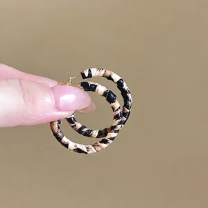 Détails de boucles d'oreilles créoles léopard avec clous dorés et texture sauvage