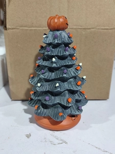 Macro detail of Halloween ceramic tree featuring glowing bulbs and orange pumpkin topper