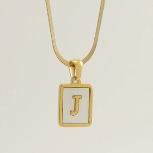 Macro shot of gold square shell pendant with letter J and sleek snake chain necklace