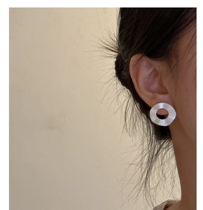 Détail macro de boucles d'oreilles argentées à texture plissée portées par un mannequin