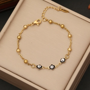 Detail view of gold beaded evil eye bracelet with enamel charms on jewelry box