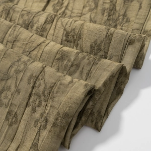 Detailed close-up of olive green jacquard fabric with elegant organza pleats texture